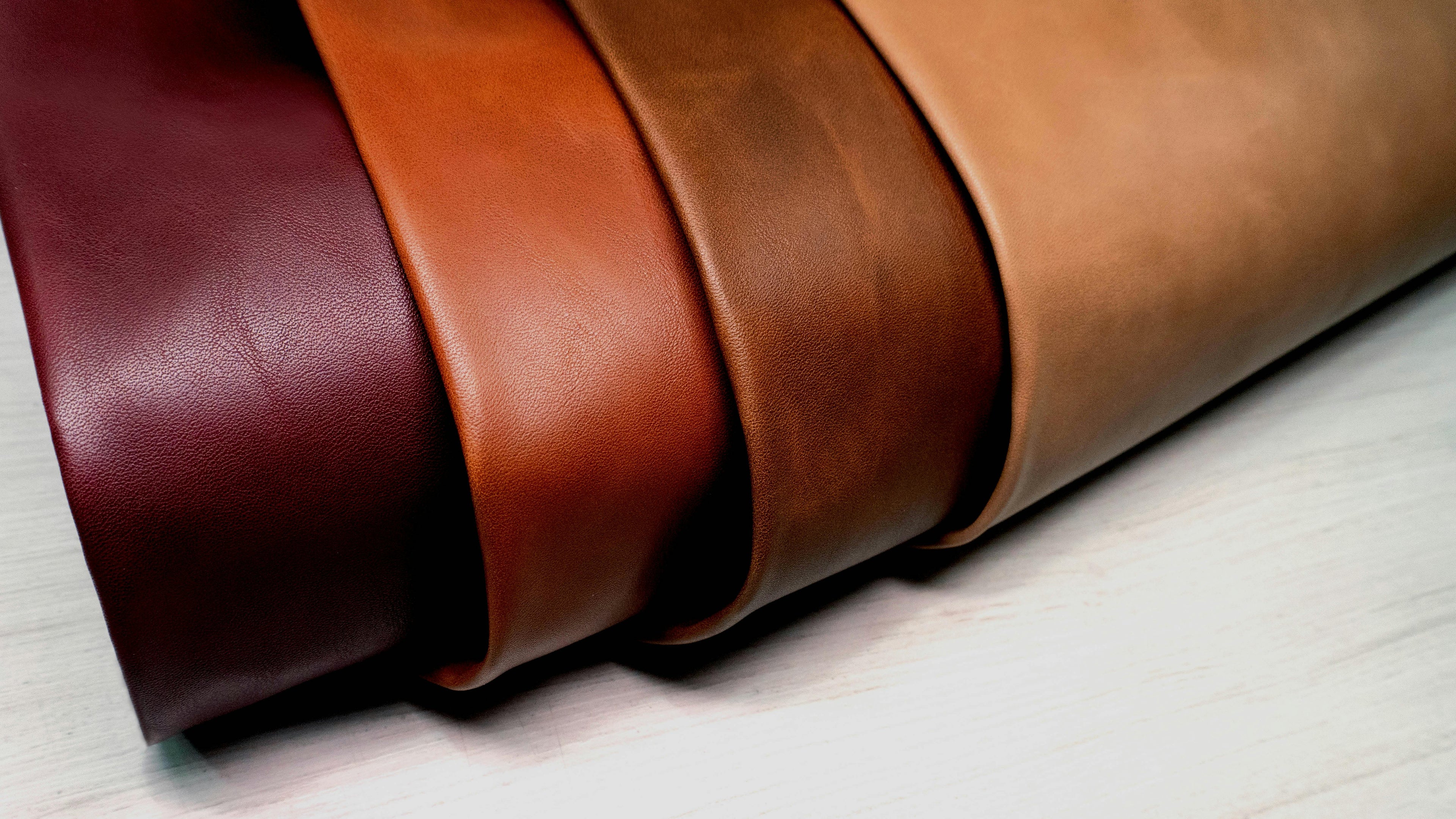 Premium genuine leather rolls in rich brown shades used for crafting ZAMRI shoes, jackets, belts, and wallets.